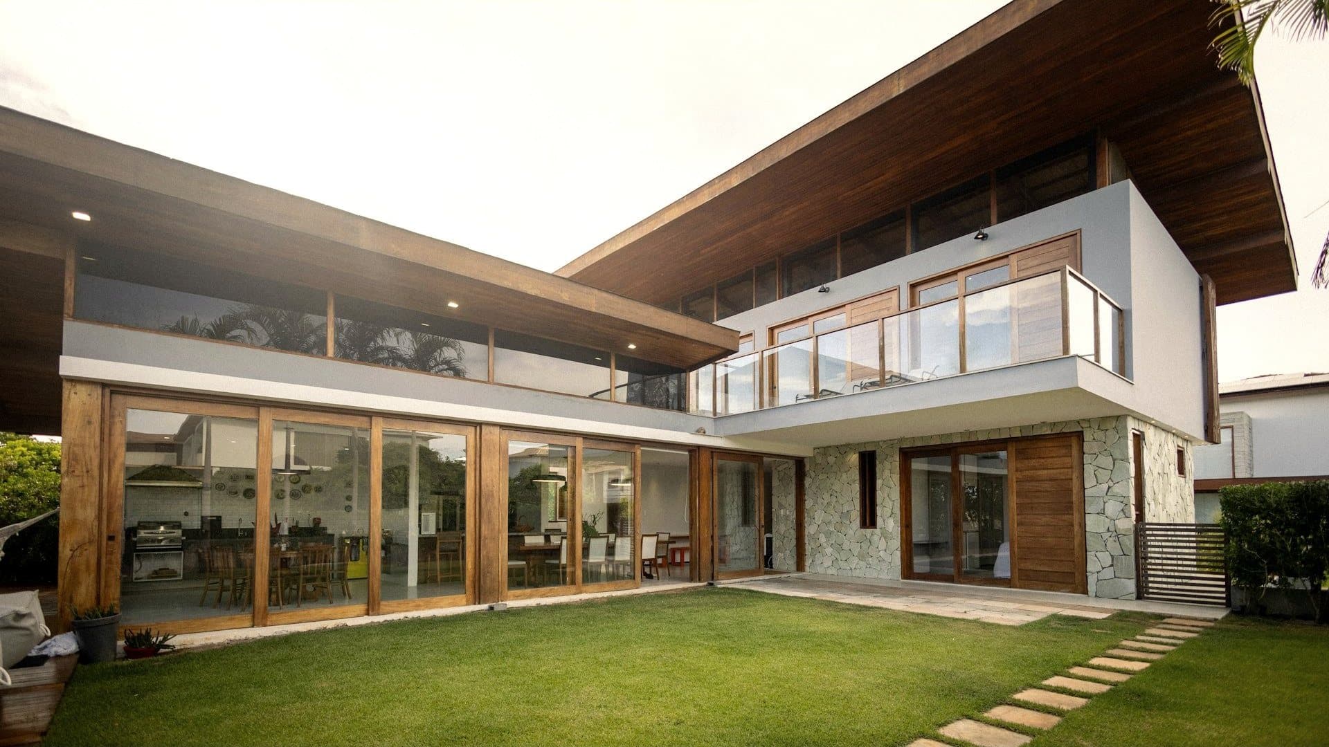 A modern home of stone, glass and timber opening to a lawn