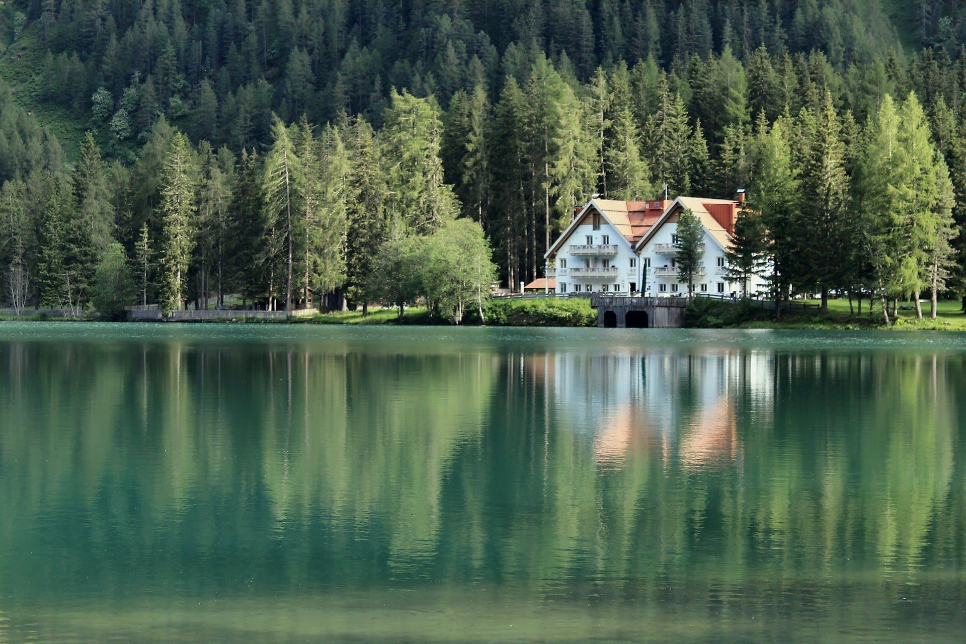 A lakefront home framed by forest and reflected in still water